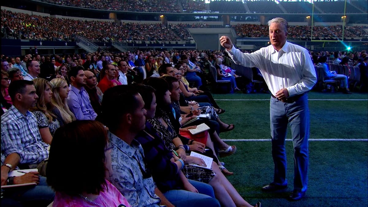 Andy Andrews speaking on stage to a large audience