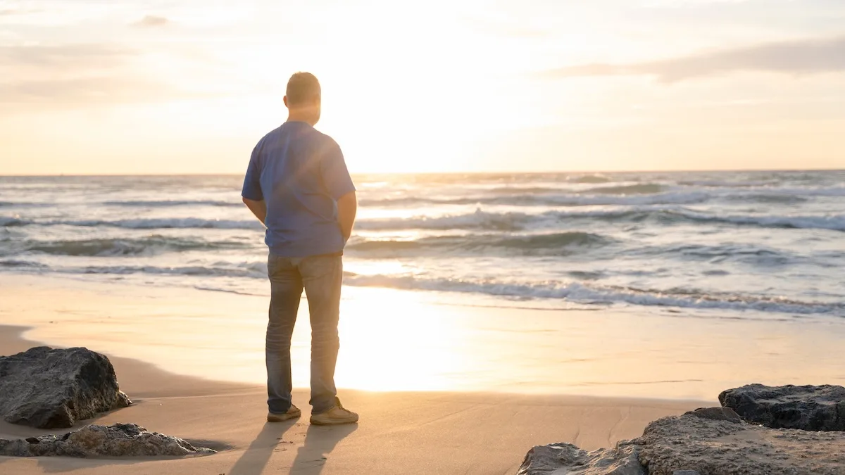 : How to gain confidence—a man standing alone at the shoreline at sunrise, looking out with quiet belief in himself