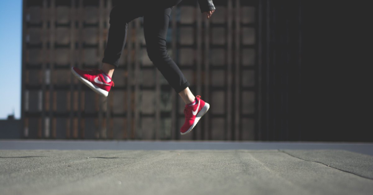 How to create your own life: a person leaping mid-stride in red sneakers across an empty city street