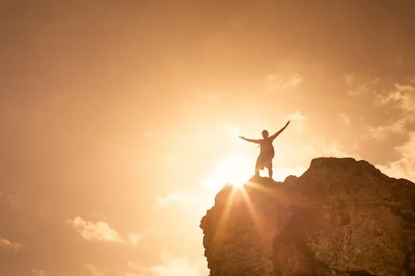 Man on top a mountain celebrating. Victory and success concept.