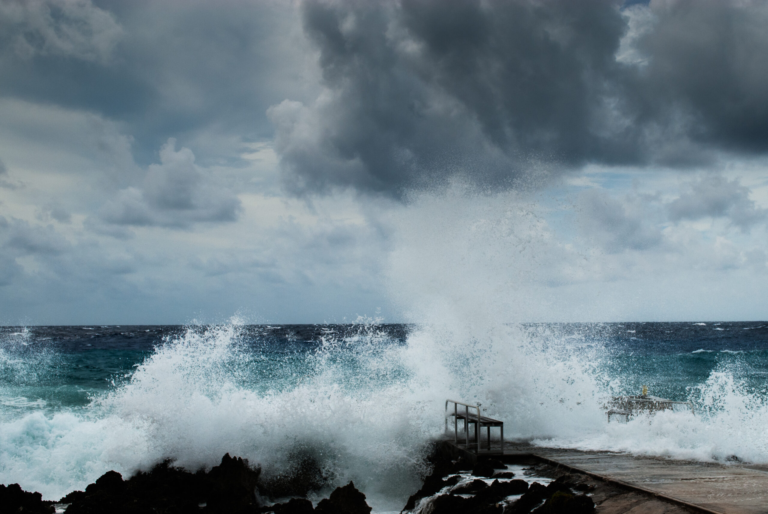 Hurricane victims: storm waves from Hurricane Irma crashing over a pier under dark clouds