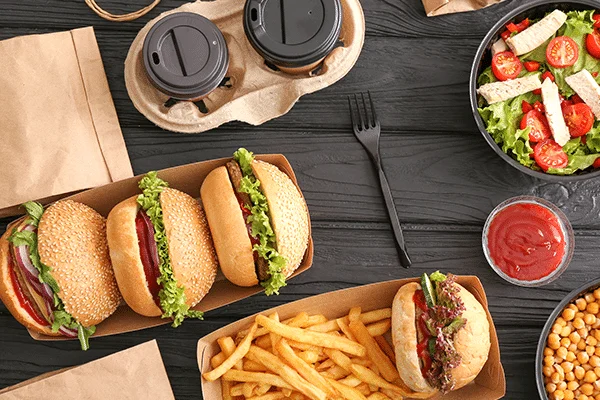 Burgers, fries, and drinks spread across a dark wooden table